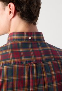 Geruite shirt met rode, blauwe, groene en gele tinten. Zachte stof met een geknoopte kraag en een lusdetail aan de achterkant.