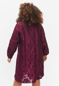 Burgundinvärd blomster spetsklänning med långa ärmar, halvgenomskinlig struktur och avslappnad passform, med ett intrikat mönster av blad över hela.