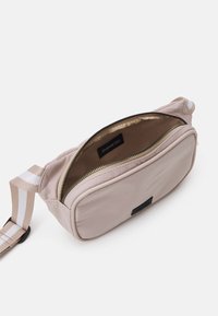 Różowa torba nylonowa z zamkiem błyskawicznym, wyściełanym wnętrzem i regulowanym paskiem w paski. Charakteryzuje się prostokątnym kształtem i minimalistycznym logo.