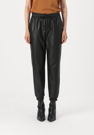 Black faux leather joggers with an elastic waistband, gathered cuffs, and a relaxed fit, paired with black ankle-high boots.