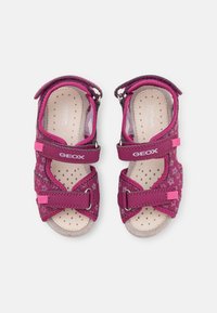 Sandalias moradas con estampado floral, correas ajustables y plantilla perforada. Cuenta con una plantilla acolchada y suela de goma para proporcionar agarre.