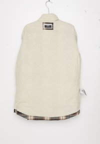 Beige fleece vest met een gestructureerd oppervlak, voorzien van een geruit flanellen zoom in bruin en wit. Inclusief een label op de achterkant van de kraag.