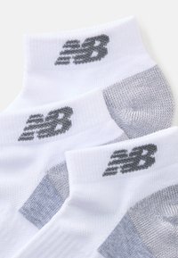 Hvite anklsokker med grå detaljer, som har et teksturert design og "NB"-logoen i grått ved skaftet og hælen.