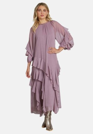 Vestido maxi morado de capas con mangas y dobladillo con volantes, hecho de una tela ligera. Llevado con botas metálicas hasta el tobillo.