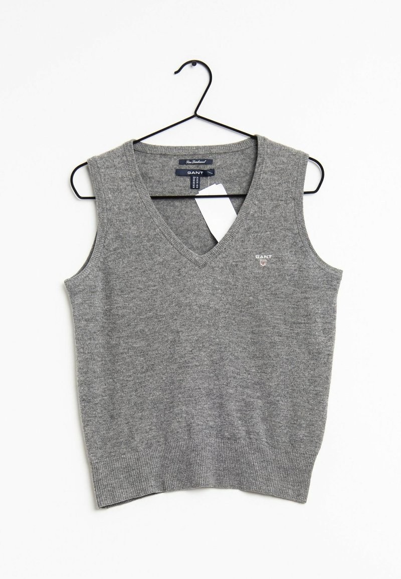 Gilet en maille gris sans manches avec col en V et logo GANT sur la poitrine, présenté sur un cintre noir sur fond blanc avec une étiquette de taille visible.