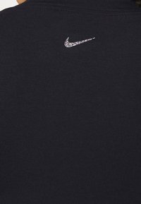 Sweat-shirt bleu marine foncé avec une texture côtelée et un logo Nike Swoosh argenté scintillant sur le haut du dos. Design simple, coupe classique.