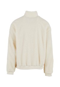 Cremefarbener Pullover mit hohem Kragen, aus flauschigem Fleece-Material. Verfügt über gerippte Bündchen und einen Taillensaum, glatte Textur.