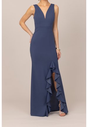 Ärmelloses dunkelblaues Kleid mit tiefem V-Ausschnitt und gerafftem hohem Schlitz an einer Seite, getragen mit Riemchensandaletten mit hohem Absatz und einem goldenen Armband.