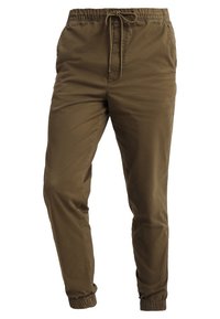 Bruna tapered byxor med elastisk midja och justerbar dragsko. Har ankelfållar och slitstark, mjuk väv.