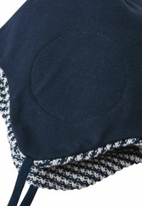Czapka dzianinowa w granatowym kolorze z teksturowanym białym i granatowym paskiem. Posiada gładką, okrągłą łatę na czubku. W zestawie sznurki do związania.