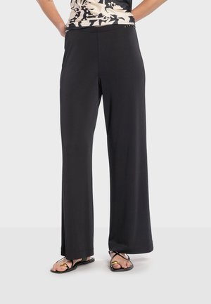 Sorte vidde-bukser lavet af blødt stof med en glat taljebånd og en lige snit. Parret med enkle sorte sandaler.