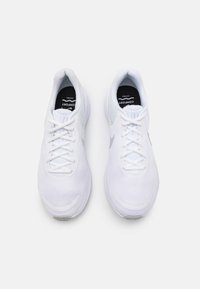 Chaussures de sport blanches avec empeigne en mesh, bout rond, fermeture à lacets, col rembourré et logo contrastant sur le côté. Semelle extérieure à coussinage doux.