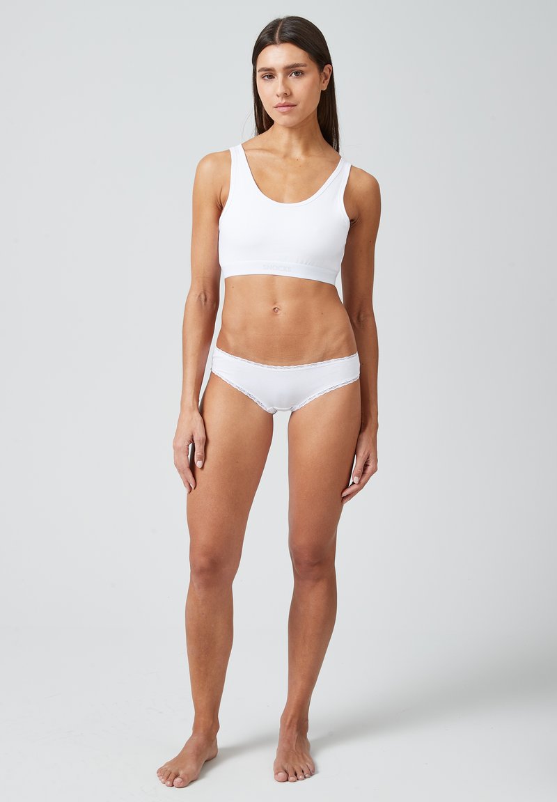Soutien-gorge en coton blanc et culotte assortie, présentant une texture lisse, un design simple et des accents en dentelle le long de la taille de la lingerie.