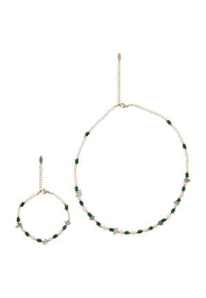Ketting en armband met witte, groene en beige kralen, voorzien van gouden ketting sluitingen en verstelbare schakels.