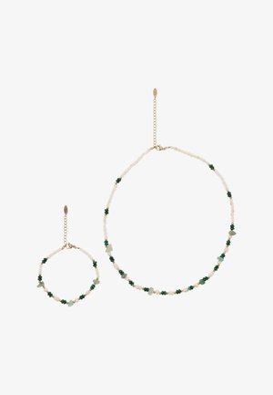 Ketting en armband met witte, groene en beige kralen, voorzien van gouden ketting sluitingen en verstelbare schakels.