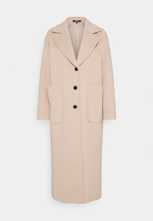 Long manteau beige avec larges revers, trois boutons noirs et grandes poches plaquées devant, présenté sur fond blanc.