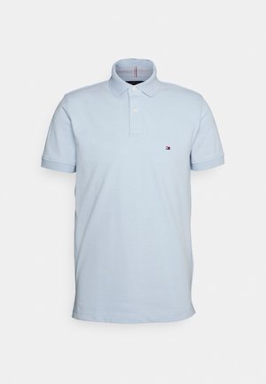 Polo shirt bleu clair à manches courtes, col, deux boutons et un petit logo brodé sur la poitrine. Tissu en mélange de coton.