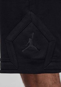 Melni sporta šorti ar dimanta formas akcentu un paceltu melnu Jumpman logotipu. Izgatavoti no tekstūrētas auduma ar redzamām šuvēm.