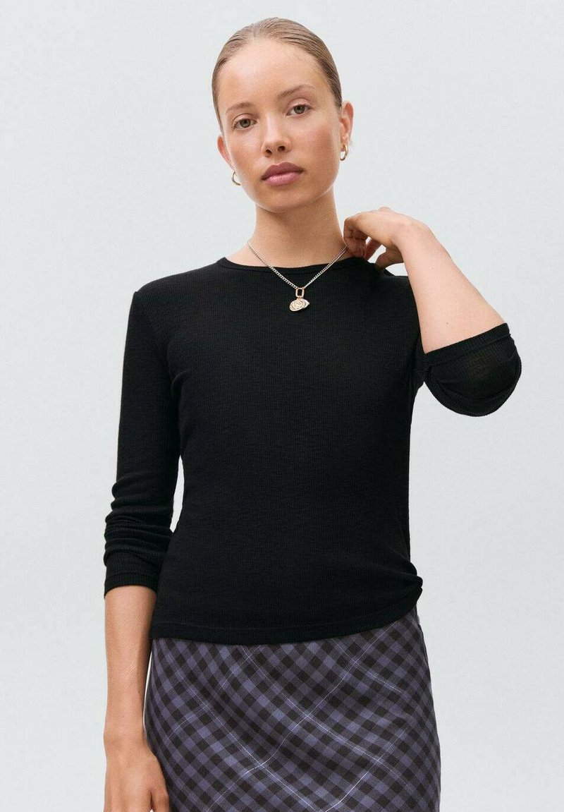 Černý žebrovaný top s dlouhým rukávem a kulatým výstřihem, přiléhavý střih, spárovaný s kostkovanou sukní v purpurové a černé barvě.