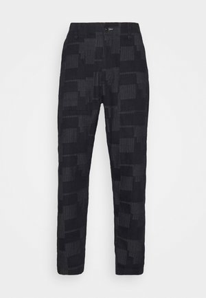 Pantalon noir à motifs avec un design texturé comprenant des formes verticales et rectangulaires. Tissu lisse avec une coupe ajustée et des passants pour ceinture.
