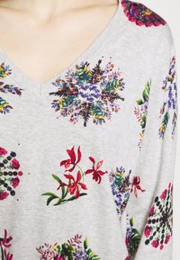 Gray v-neck sweater featuring a floral print with colorful flowers, including reds, purples, and greens, on a textured fabric.