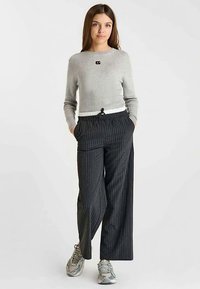 Grijze geribbelde trui met een klein logo, gecombineerd met zwarte wijde broek met krijtstrepen. Gemaakt van gemengde materialen met een elastische tailleband.