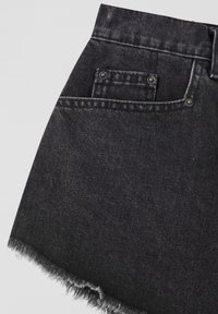 Black denim shorts with a frayed hem, featuring a front pocket and silver button closure. Textured fabric with a smooth finish.