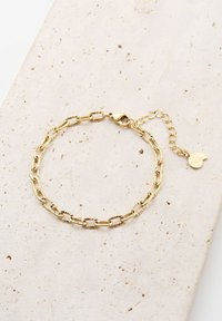 Pulsera de oro con eslabones alargados con patrones texturizados, un cierre de langosta y una cadena ajustable con un pequeño charm.