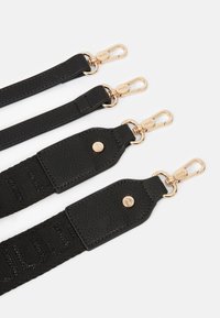 Czarny zestaw pasków z teksturowanymi skórzanymi końcówkami i złotą metalową hardware. Regulowana długość z plecioną tkaniną.