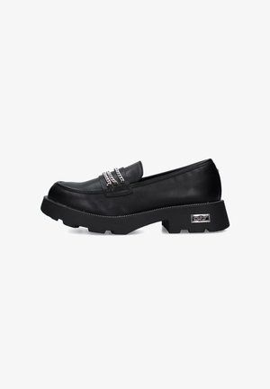 Mocassino in pelle nera con suola in gomma spessa, caratterizzato da dettagli in catena metallica, cuciture decorative e una punta arrotondata.