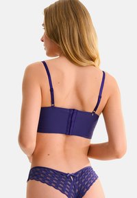 Ensemble de lingerie violet comprenant un haut cropped à côtes avec bretelles ajustables et un culotte taille basse avec un motif à carreaux et un détail nœud.