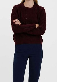 Burgundské pletené svetr s texturovaným károvým vzorem, kulatým výstřihem a žebrovaným lemem, doplněný o tmavě modré slim kalhoty.