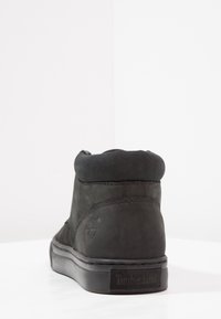 Mustat mokkasiinisen nilkkakengät, joissa on pyöreä kärki, pehmustettu kaulus, kontrastiväriset saumat ja kumipohja. Varressa on logo.