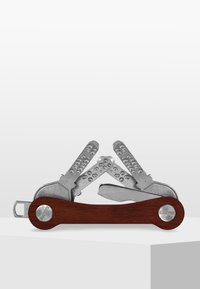 Multiverktyg med silverfärgade blad av metall och ett handtag av mörkt trä. Har flera vikbara verktyg och en mjuk yta, med framträdande detaljer i hårdvara.