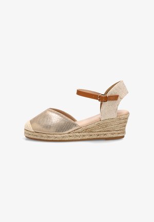 Sandalia cuña dorada con puntera cerrada, suela de cuerda trenzada, tira de talón texturizada beige y correa marrón ajustable con hebilla en el tobillo.