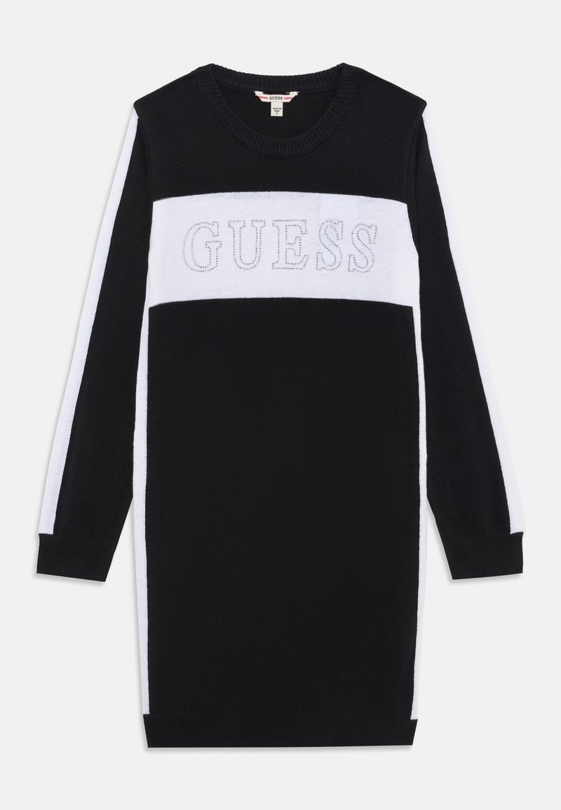 Juoda ir balta megzta suknelė su ilgomis rankovėmis. Ant krūtinės yra didelis sidabrinis "GUESS" logotipas ir kontrastingi dryžiai.