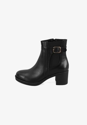 Schwarze Leder-Stiefelette mit einem klobigen Absatz, seitlichem Reißverschluss, elastischem Einsatz und einem dekorativen Schnallenakzent am Knöchelriemen. Glatte Textur.