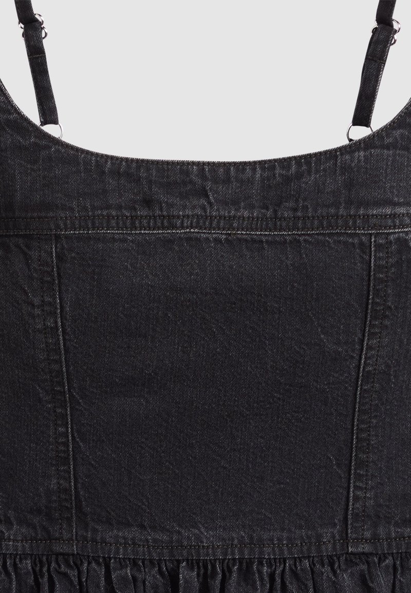Zwarte denimjurk met verstelbare schouderbandjes en een geplooide rokdetaillering aan de onderkant.