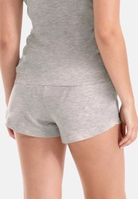 Szare bawełniane szorty o gładkiej fakturze, z dopasowanym pasem i zaokrąglonymi brzegami, pokazane od tyłu z minimalnymi detalami.