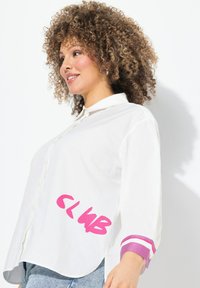 Witte overhemd met knopen en een roze "CLUB" graphic aan de voorkant. Heeft paarse gestreepte manchetten en een zachte, lichte textuur.