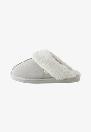 Chausson gris clair à enfiler avec une doublure et une semelle en fausse fourrure blanche douce portant l'étiquette "NEXT,", vu de côté sur fond blanc.