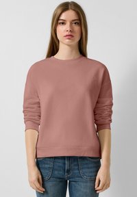 Stofrozen rozen sweatshirt met een ronde hals, ribbelmanchetten en onderrand. Bevat een klein logo op de borst en heeft een losse pasvorm. Gecombineerd met blauwe jeans.