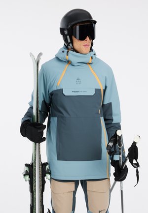 Skijacke in Blau und Grau mit orangefarbenen Akzenten, leichtes Material, verstellbare Kapuze, Taschen mit Reißverschluss, getragen mit schwarzen Handschuhen und Skiern.