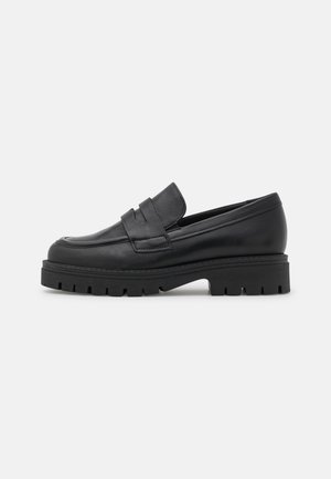 Sort læderloafer med kraftig mønstersål og moc-toe-syning, slip-on-design med et stropdetalje over vristen.