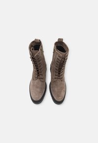 Bottines en suede marron avec un design à lacets, fermeture éclair et semelles en caoutchouc noir contrastantes. Surface texturée et bout rond.