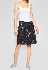 Mustapuku, jossa on vaaleanpunaisia ja vihreitä kukkakuoseja. Valmistettu sileästä kankaasta. Varustettu leveällä mustalla vyötärönauhalla ja polvimittaisella leikkauksella.