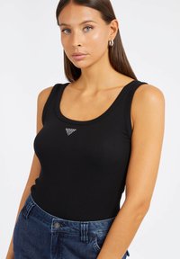 Débardeur noir à côtes avec un col rond et un petit détail en rhinestone triangulaire sur la poitrine, associé à un short en denim noir taille haute.