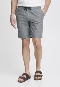 Gråstripete shorts med snor i livet, sidelommer og en avslappet passform. Kombinert med brune sandaler med to justerbare stropper.