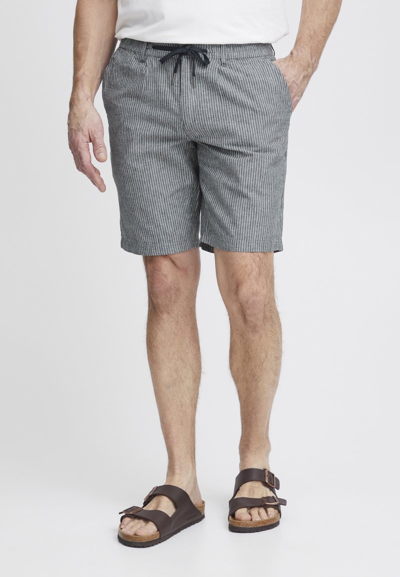 Gråstripete shorts med snor i livet, sidelommer og en avslappet passform. Kombinert med brune sandaler med to justerbare stropper.