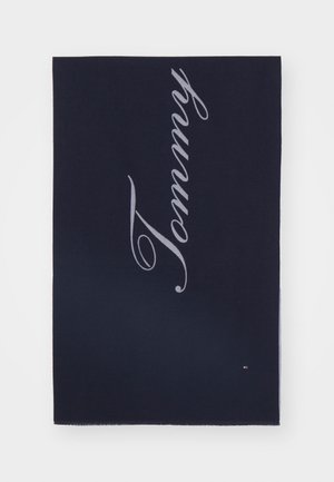 Écharpe rectangulaire bleu marine avec "Tommy" écrit en grandes lettres cursives gris clair en diagonale.